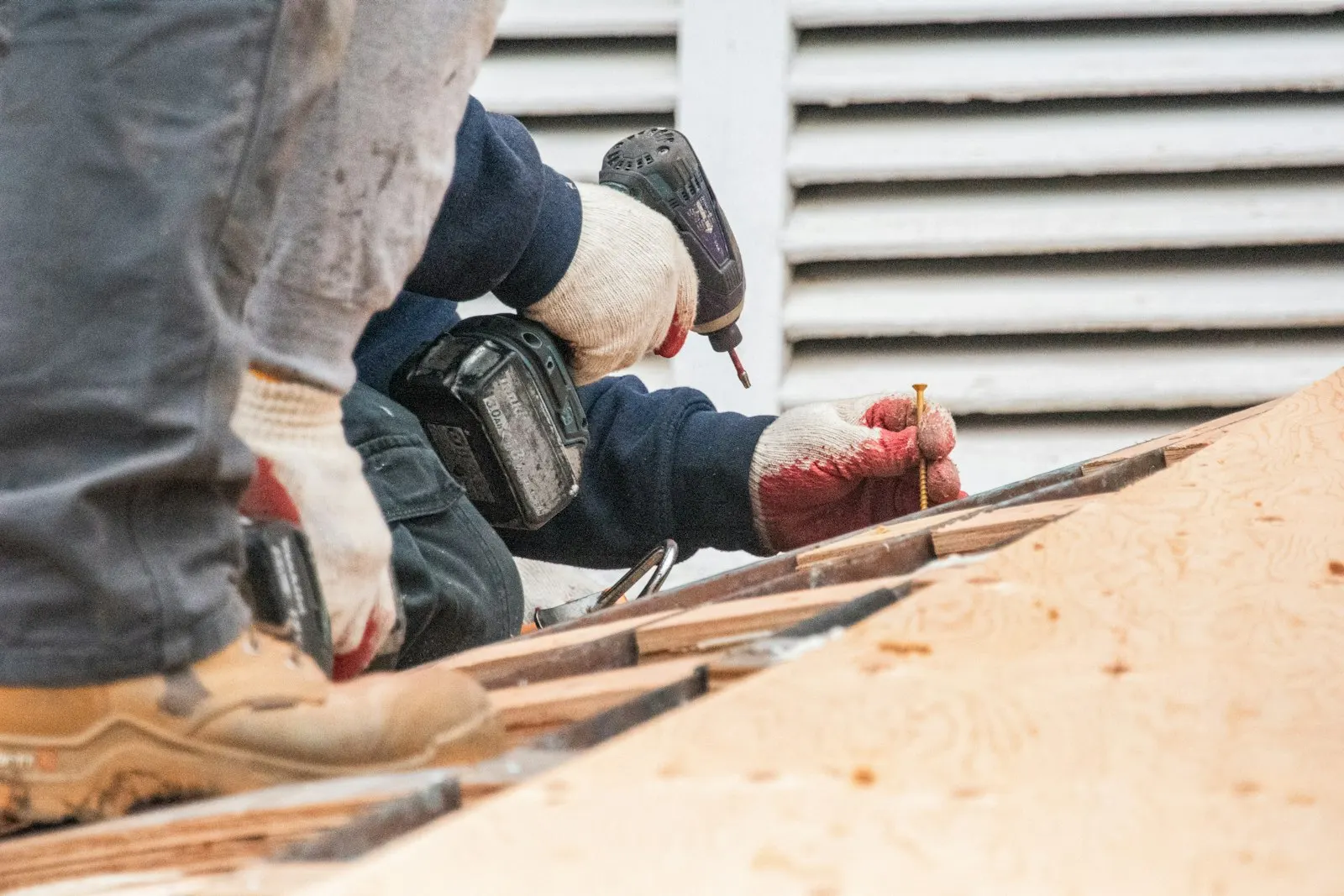 Tradesperson drilling on a roof with work gloves